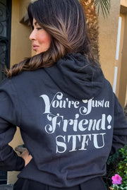 Picture of Emily Simpson from the back wearing a black hoodie with the words "You're Just a Friend! STFU" written in large  white font on the back of the sweatshirt. 