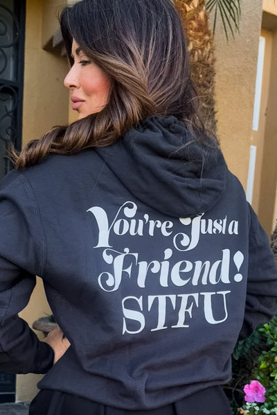 Picture of Emily Simpson from the back wearing a black hoodie with the words "You're Just a Friend! STFU" written in large  white font on the back of the sweatshirt. 