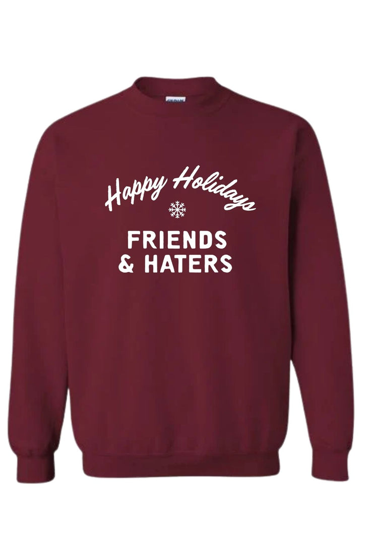 Pciture of a red crewneck sweatshirt with "Happy Holidays Friends & Haters" printed on middle front of sweatshirt in white writing. 