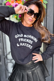 Woman in a black crewneck sweatshirt  that says good morning friends and haters